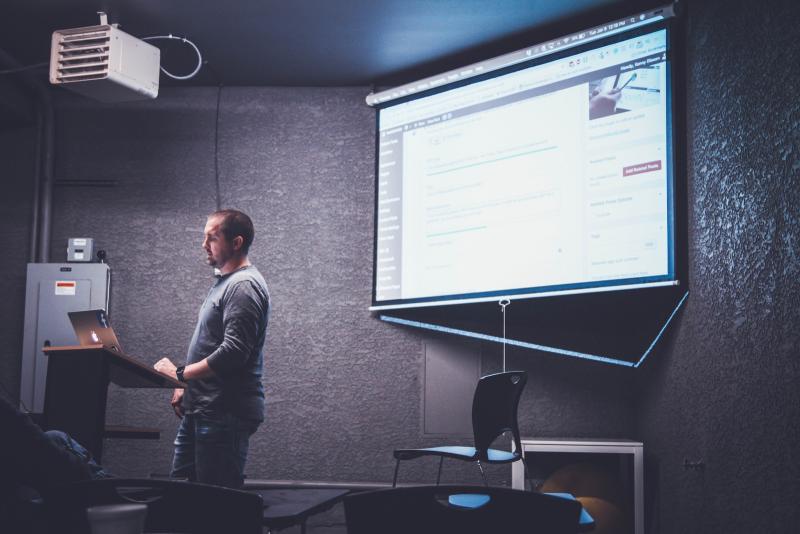 man-at-podium-screen-presentation-behind-him